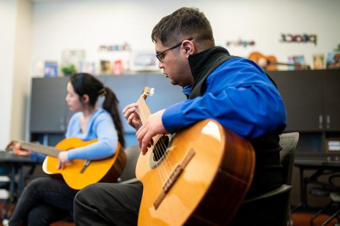 A male student playing the guitar.